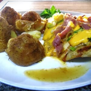Pechuguitas cubiertas con queso cheddar, verdeo y jamón crudo con papas rotas