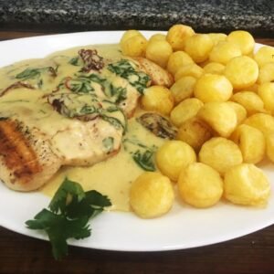 Pollo con salsa crema de rúcula y tomates secos con papas noissette