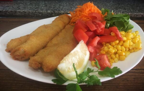 Filet de merluza al milanesa con ensalada de rúcula, tomate, zanahoria y choclo