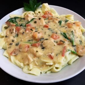 Tagliatellis caseros con crema de rúcula, trocitos de pollo y tomate concasé