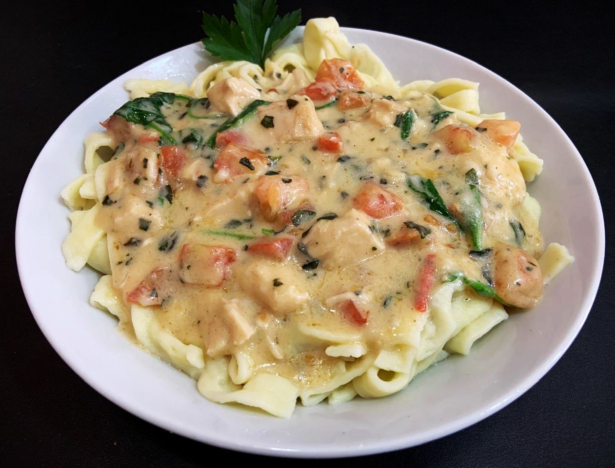 Tagliatellis caseros con crema de rúcula, trocitos de pollo y tomate concasé